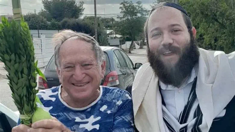 Chabad emissary helps a man wave the Four Species 