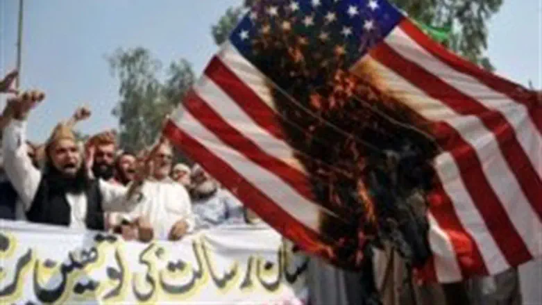 Pakistani Muslim protesters burn a US flag du