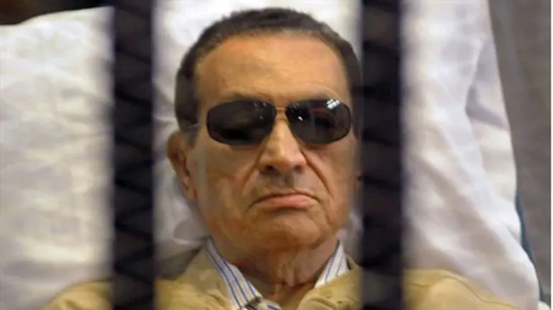 Mubarak sits inside a cage in a courtroom 