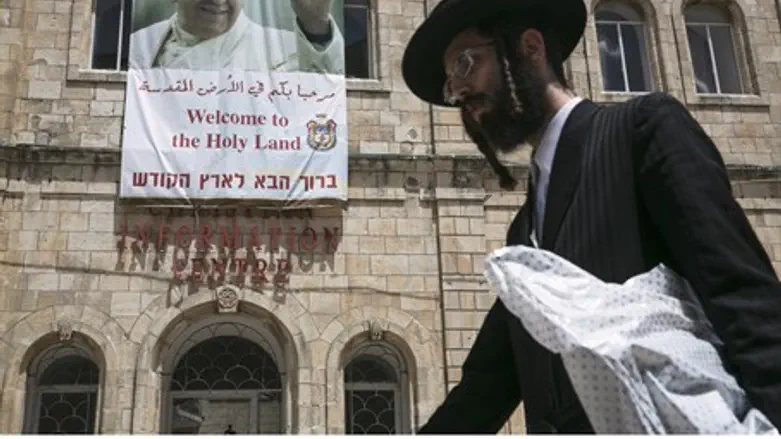 Hareidi man walks past a poster of Pope Franc