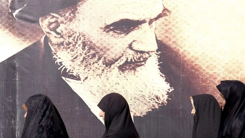 Iranian women by a poster of Ayatollah Khomeini