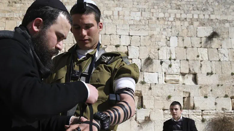 Soldier puts on tefillin at the Kotel