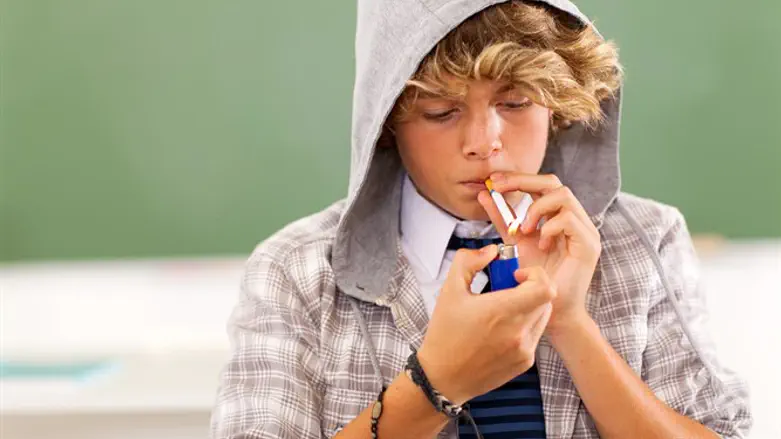Teenage boy lights a cigarette