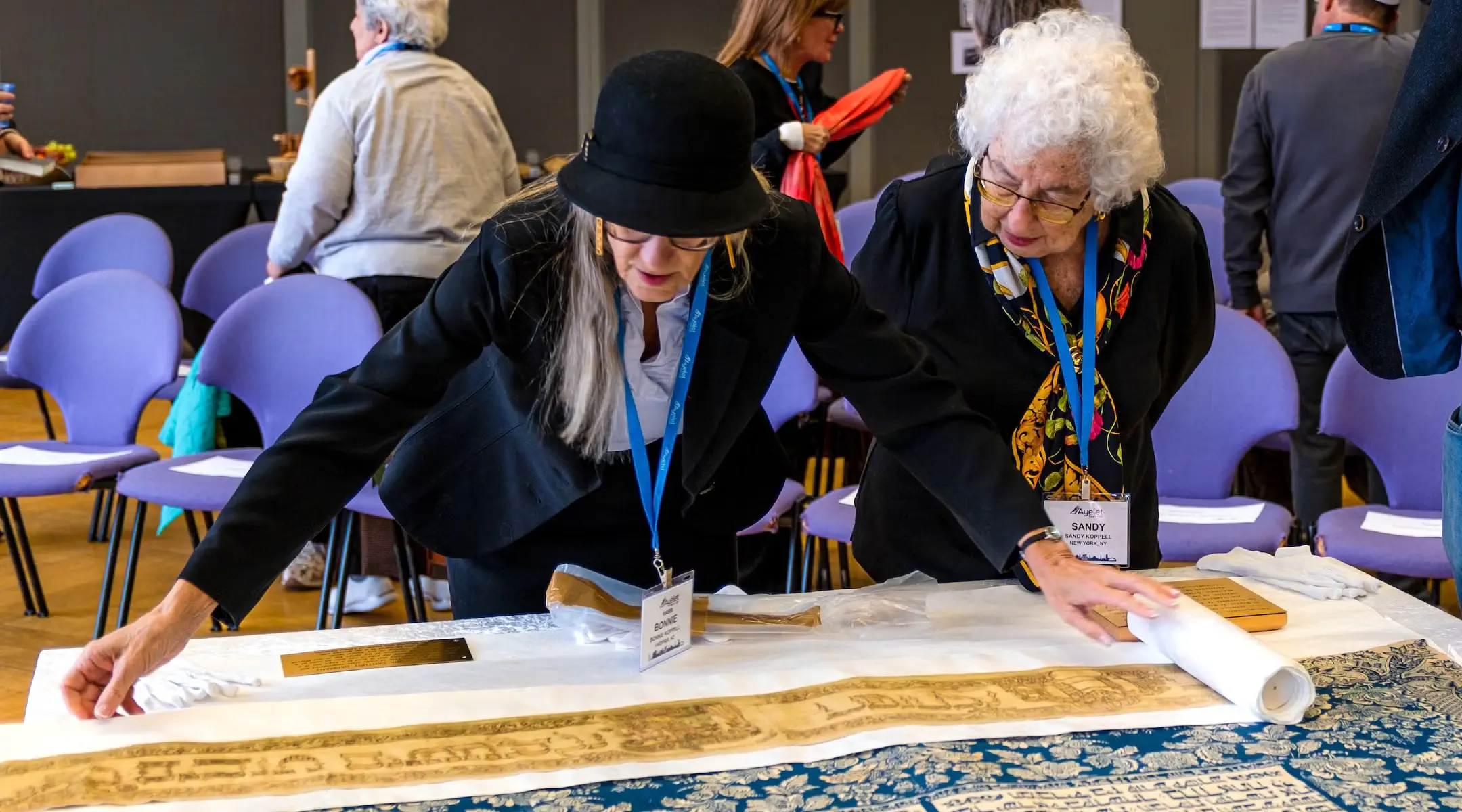 Bonnie Koppell, left, and Sandy Koppell examine the Torah curtain (parochet) and Torah wimple during the handover ceremony at the New Synagogue Berlin-Centrum Judaicum, Oct. 22, 2026.