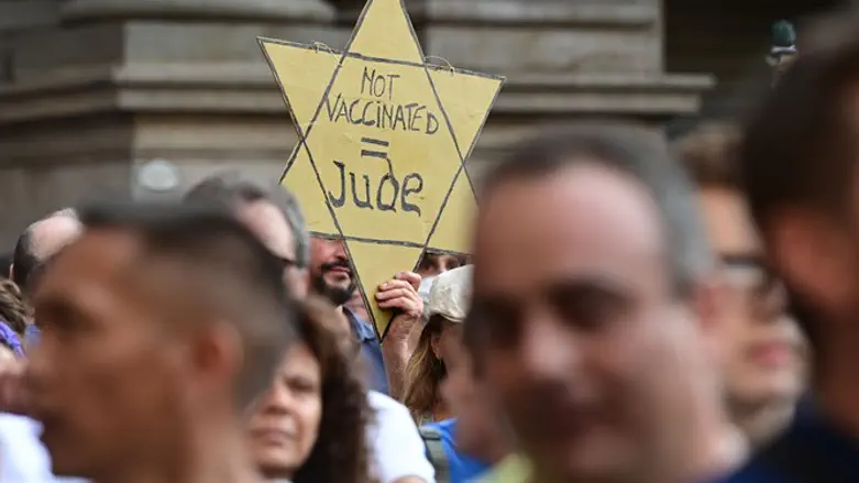 A protester holds a yellow star reading "Not Vaccinated = Jew" as protesters tak