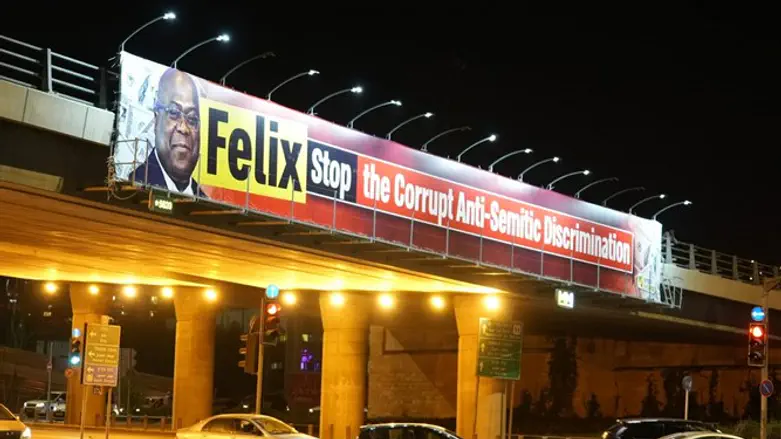 Cars travel under a bridge criticizing Congolese President Felix Tshisekedi in J