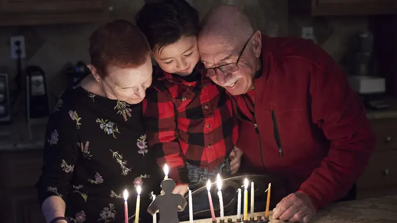 Granparents and grandson lighting Hanukkah Candles
