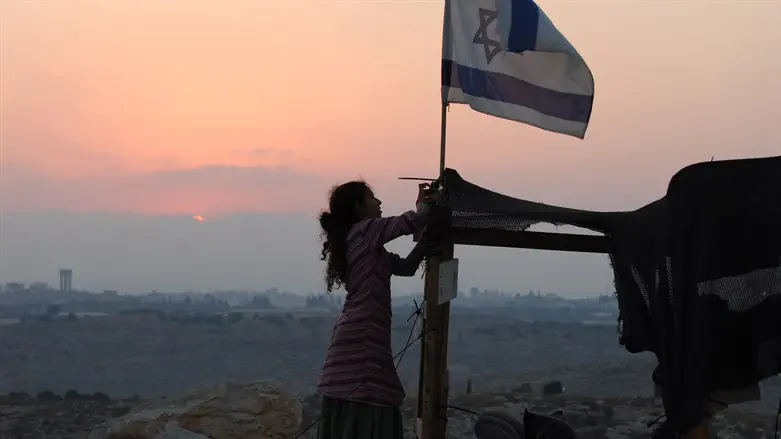 Jewish girl raises Israeli flag at the Israeli village of Avnei Hefetz, Samaria