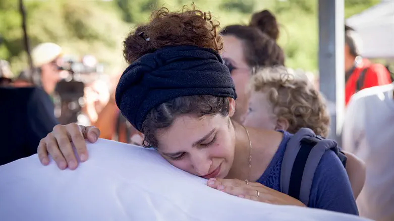 Meir Tamari's widow, Tal, embraces her husbands body during the funeral