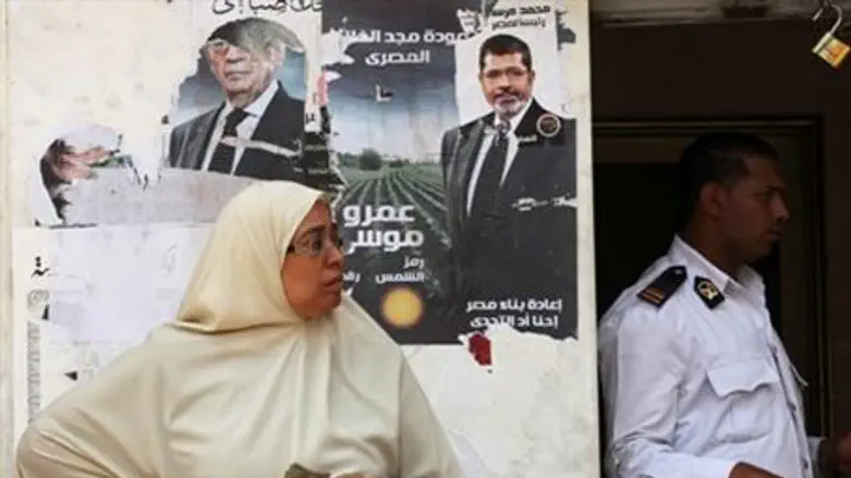 An Egyptian woman stands in front of posters 