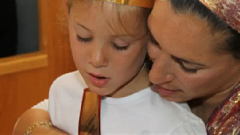Mother and daughter read from prayer book.