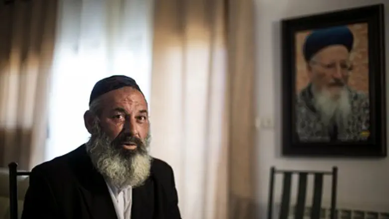 Rabbi Avraham Sinai in front of a picture of former Israeli Chief Rabbi Mordechai Eliyahu
