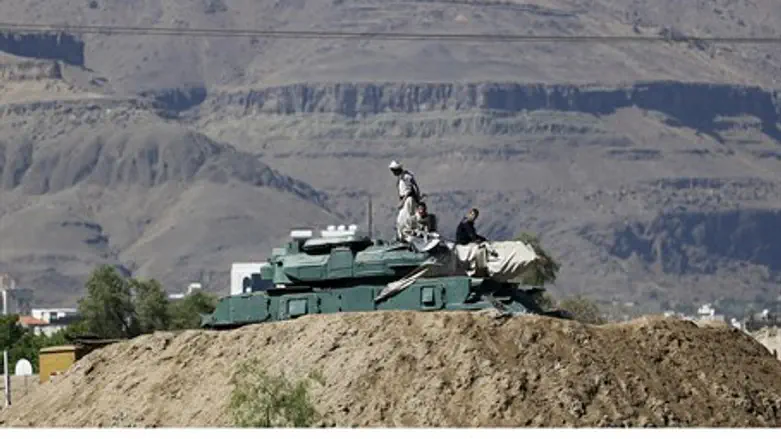 Houthi fighters sit on a tank in Yemen