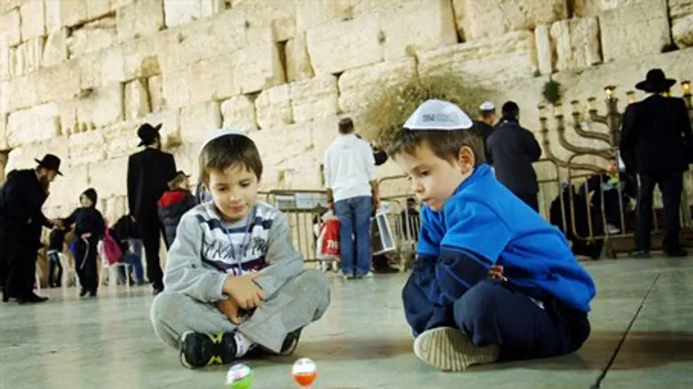 Jewish kids play with dreidels by the Hanukkiya at the western wall, in Jerusalem's Old Ci