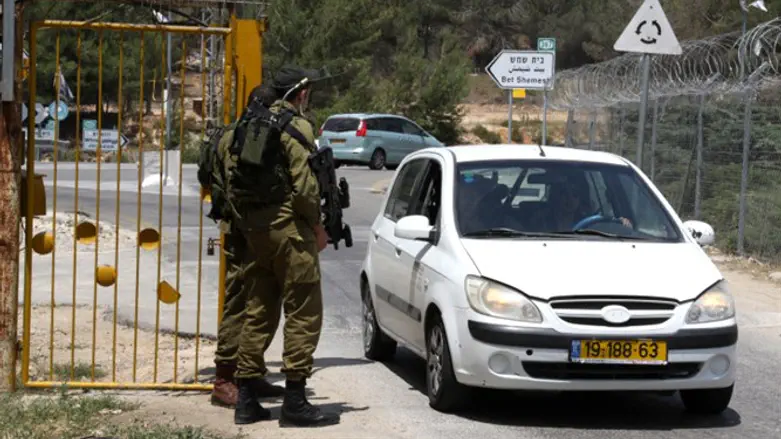 Israeli soldiers stand guard at the entrance to Kibbutz Kfar Etzion