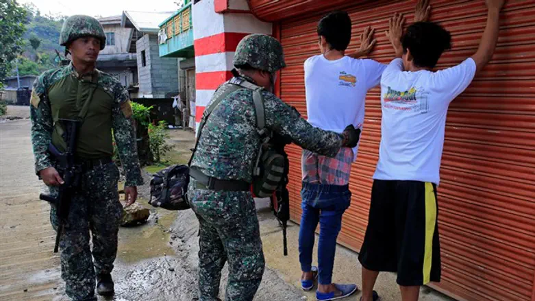 Government soldier frisks resident who evacuated his home in Sarimanok village, Marawi