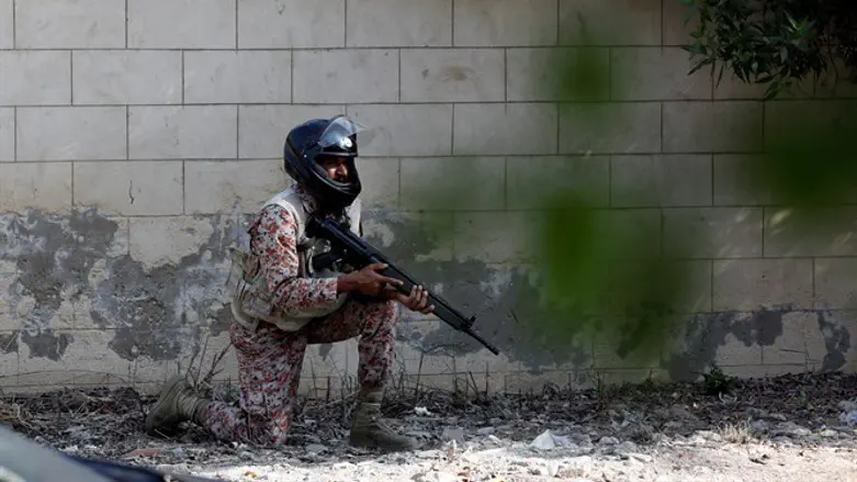 Pakistani soldier crouches behind wall during Chinese embassy attack