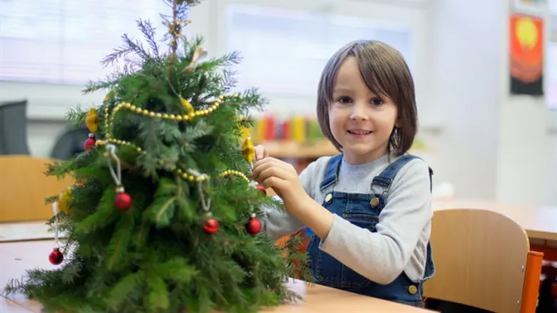 Child decorates Christmas tree in school (illustrative)